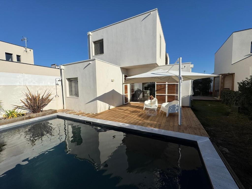 une personne assise dans une chaise à côté d'une maison dans l'établissement Villa d'architecte aux portes de la mer, à Pérols