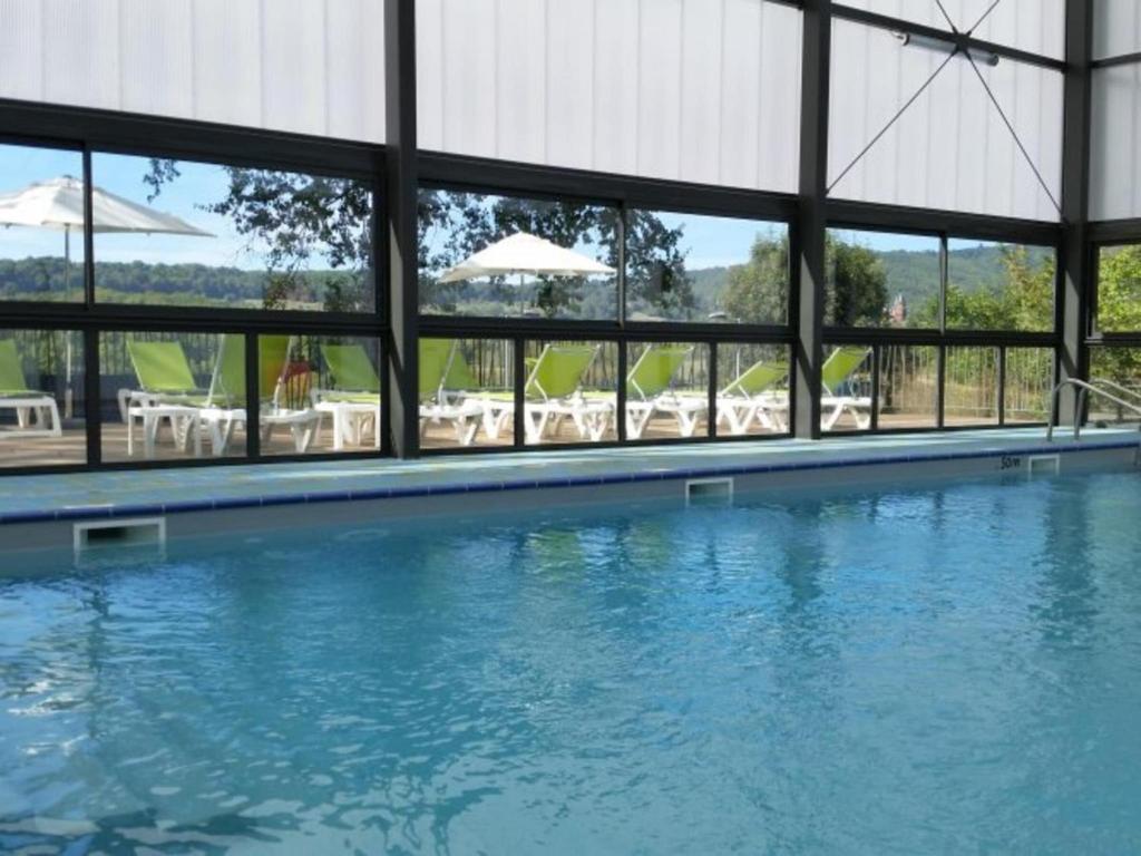 une piscine avec tables et chaises dans un bâtiment dans l'établissement Gîte in Collonges near Dordogne Valley, à Meyssac