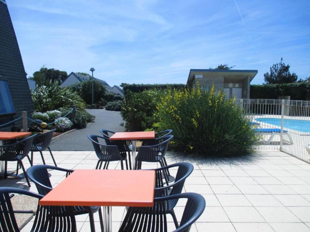 un patio avec tables et chaises à côté d'une piscine dans l'établissement Gîte in La Turballe by the Sandy Beach, à La Turballe