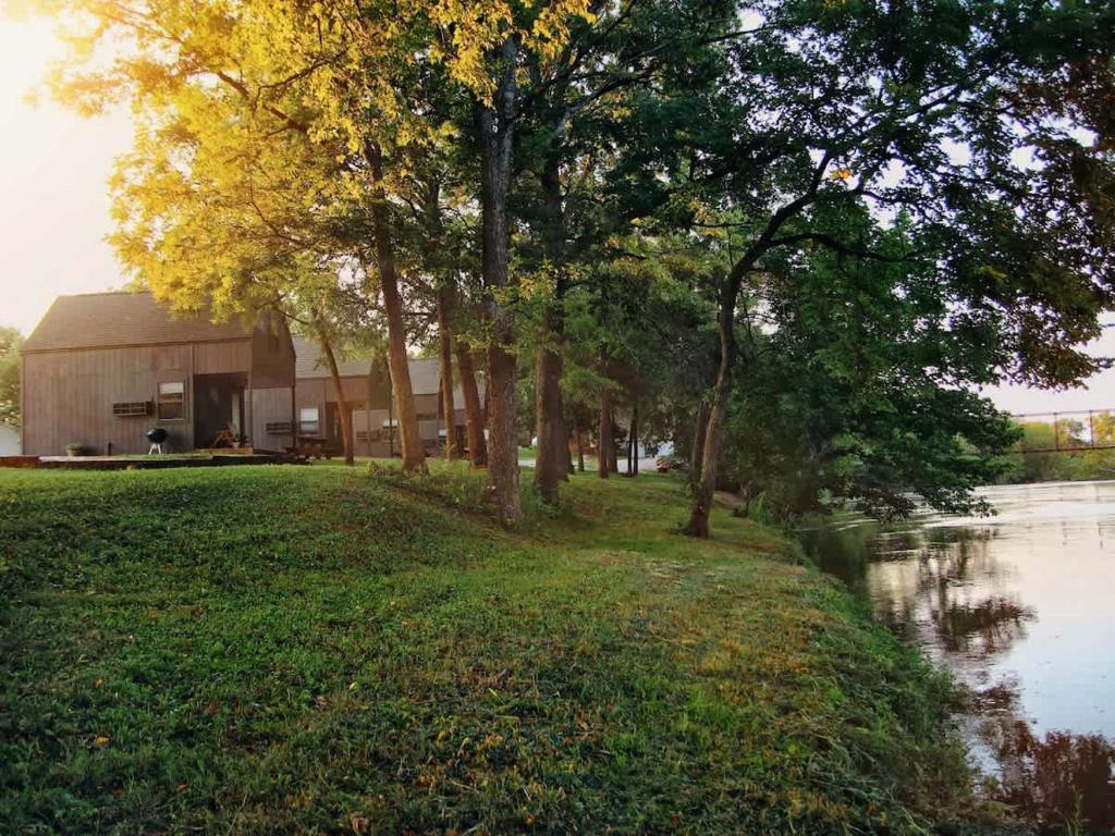 un edificio junto a una masa de agua con árboles en Riverfront Getaway Cabin #2 - Sleeps 5, en Stockton