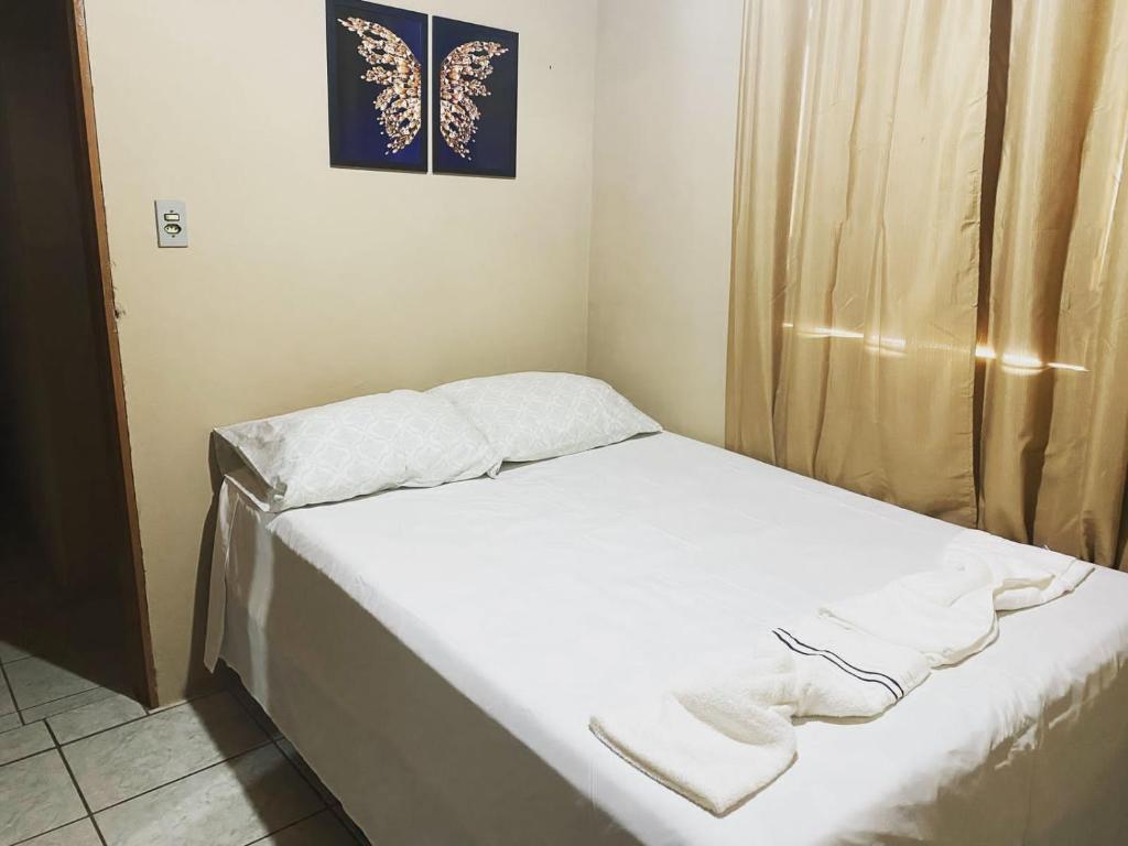 a small bed in a room with white sheets at Casa da vila in Lençóis