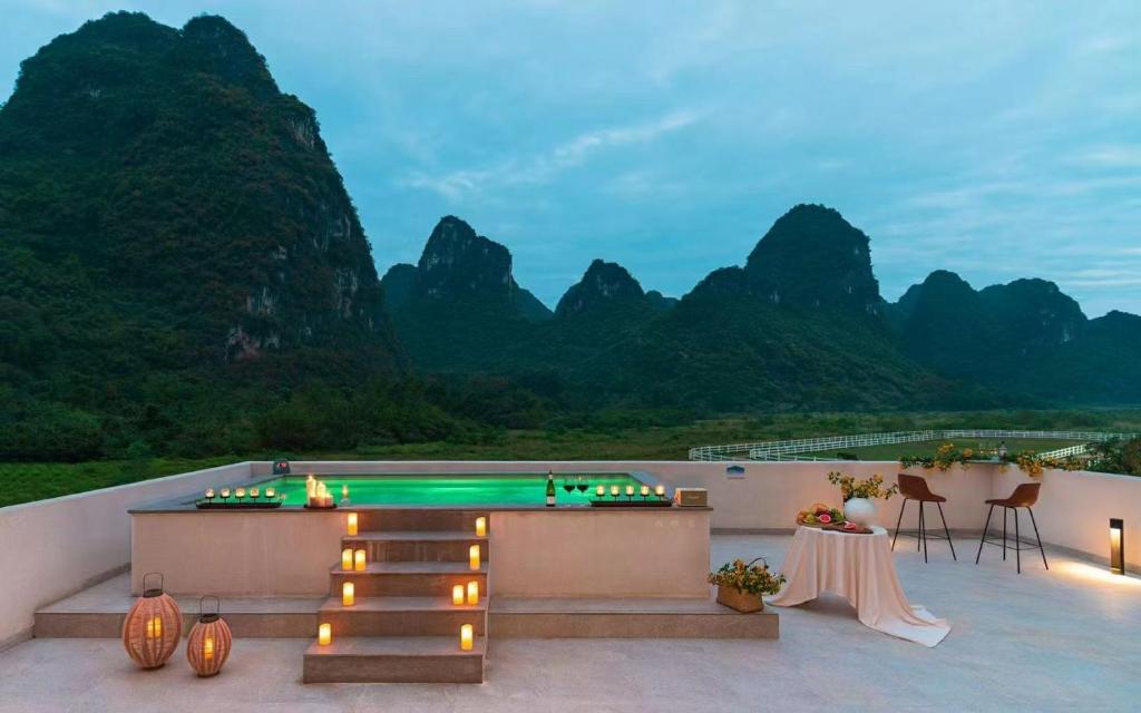 a balcony with a table and a view of mountains at Yangshuo One Thousand and One Courtyard Views B&B in Yangshuo