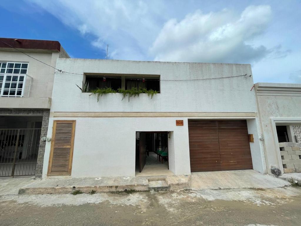 a white house with two windows and a garage at Casa colibrí in Río Lagartos