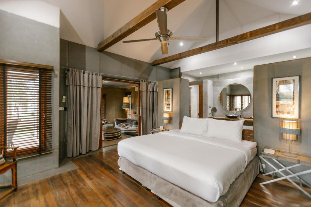 a bedroom with a large white bed and a bathroom at The Farmhouse at Polo Escape in Ban Pong