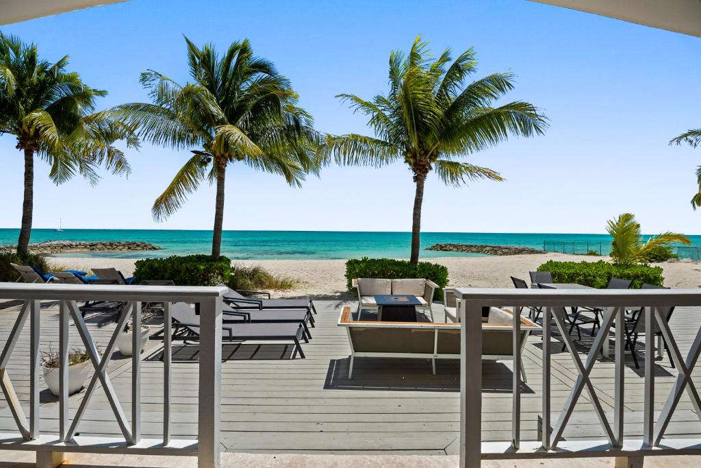 a deck with chairs and palm trees on the beach at White House - Exclusive Luxury Beachfront Villa - Private White Sand Beach in Nassau