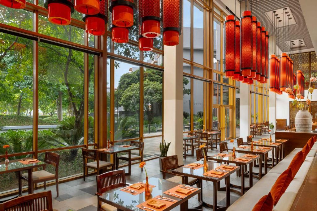 un ristorante con tavoli, sedie e ampie finestre di Angsana Lang Co a Lăng Cô