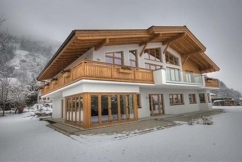 a house with a wooden roof in the snow at Chalet Apartment Ski and Golf by Kaprun Rentals in Zell am See