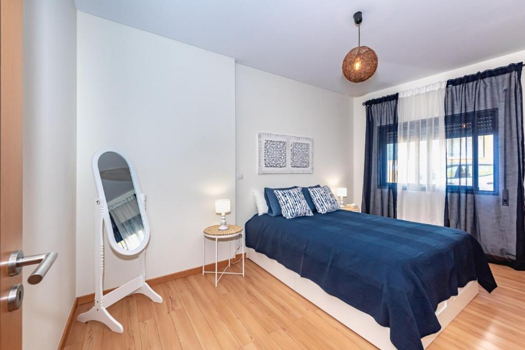 a bedroom with a blue bed and a mirror at Casa da Cortiça in Seixal