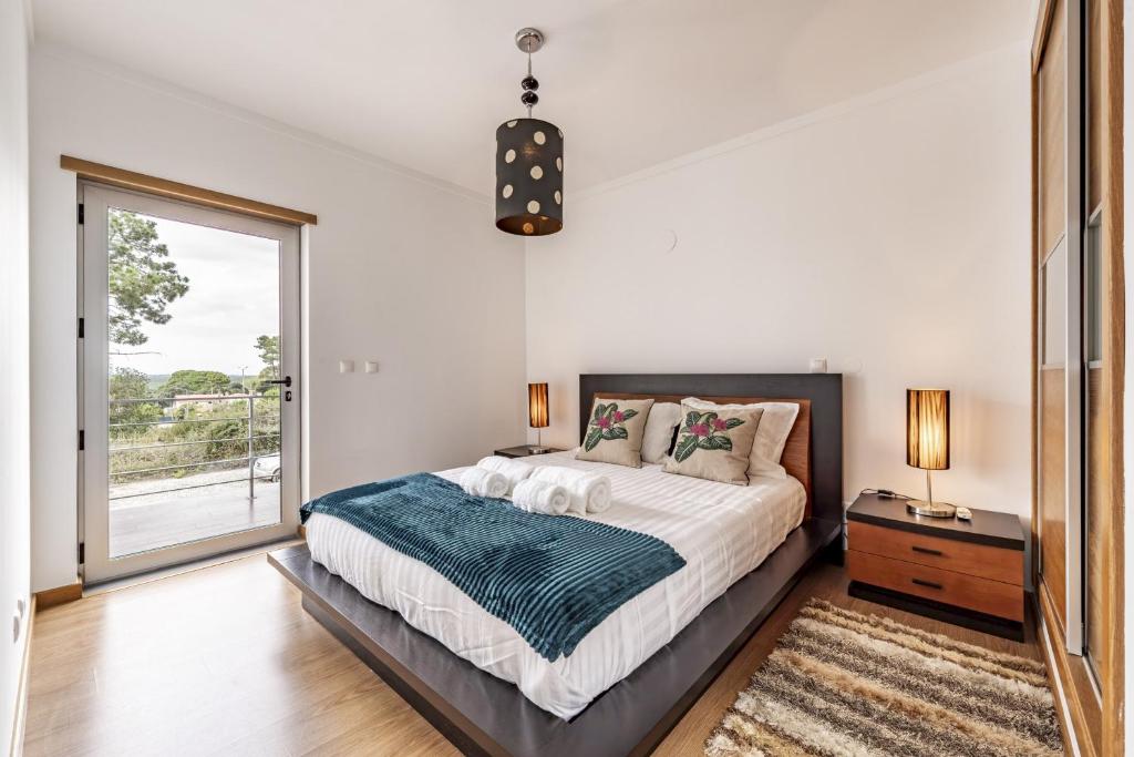 a bedroom with a bed and a large window at Serra e Mar Refuge in Sesimbra - Family Friendly home near the Arrábida Beachs in Sesimbra