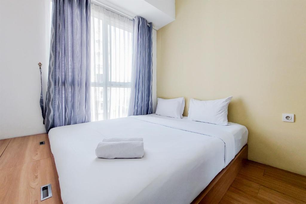 a white bed in a room with a window at Strategic and Restful 1BR at Casa De Parco Apartment By Travelio in Tangerang