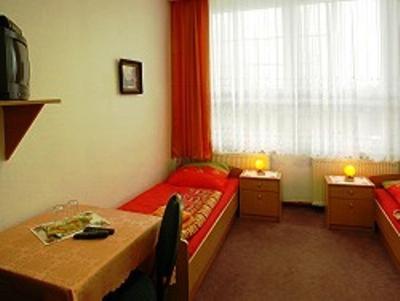 プレンツラウにあるGaststätte & Pension Am Tangerのベッド、テーブル、窓が備わる客室です。