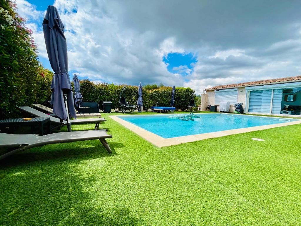 een zwembad met een parasol en stoelen naast een tuin bij Villa proche du centre-ville de Porto-vecchio et de ses plus belles plages in Porto-Vecchio
