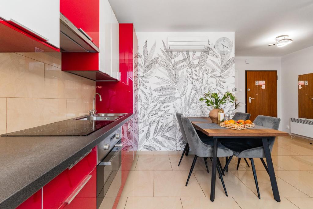 a kitchen with a wooden table and red cabinets at APARTAMENTY MIERZEJA - BALTIC PARK STEGNA, 33m2-57m2, 500 m od plaży, Bezpłatny Meleks in Stegna