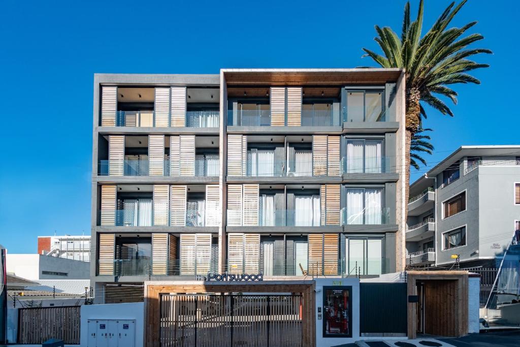 un edificio de apartamentos con una palmera delante en The Portswood by Stay In Luxury, en Ciudad del Cabo