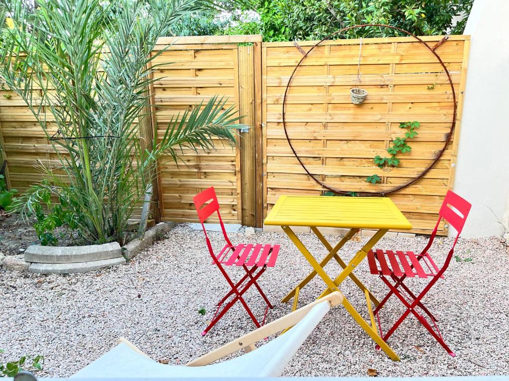 une table jaune et deux chaises rouges dans un jardin dans l'établissement Le Jardinet - Small garden in town, à Montpellier