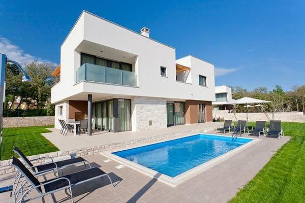 Una casa grande con piscina delante de ella. en Designvilla Mit Dachterrasse Und Panoramablick, en Karigador
