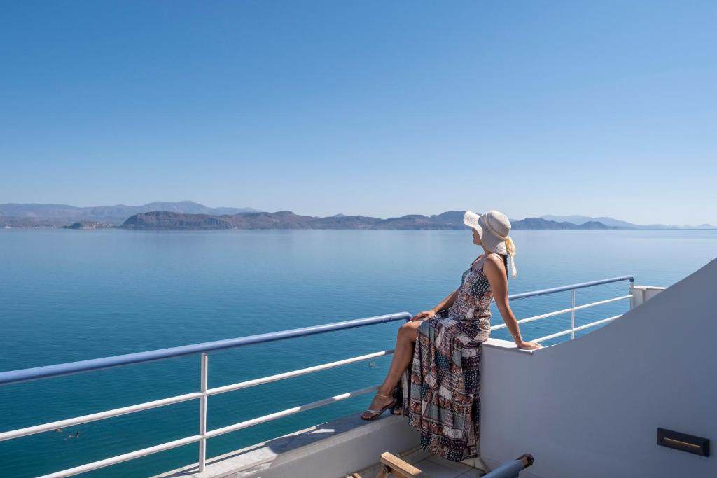 a woman sitting on the edge of a boat on the water at Luxuriöses Apartment Mit Einem Schlafzimmer Direkt Am Wasser, Meerblick in Kivérion