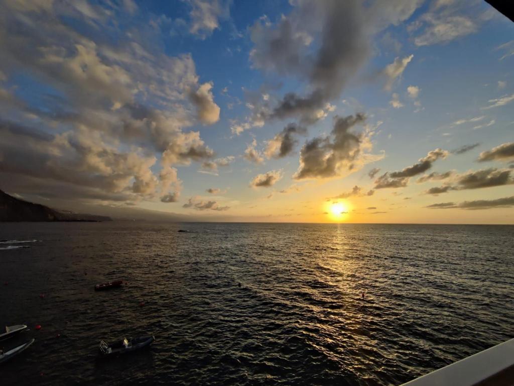 un tramonto sull'oceano con una barca in acqua di Ferienwohnung In Mesa Del Mar Mit Offenem Balkon a Puerto de la Madera