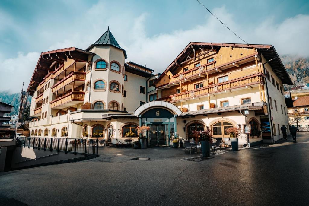 a large building with a turret on a street at Alpinresort Stubaierhof ****s in Fulpmes