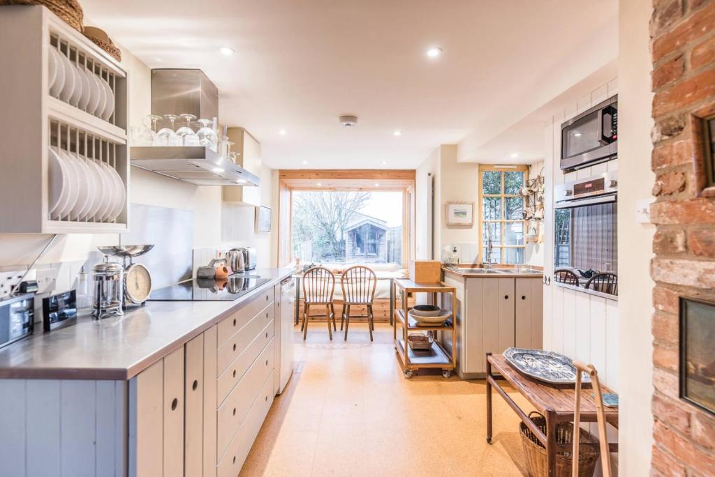 a kitchen with white cabinets and a table and chairs at Fen Cottage, Walberswick in Walberswick