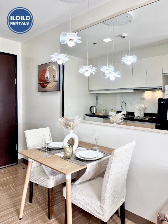 a dining room with a wooden table and white chairs at Room in Condo - Cozy, Modern and Homey, The Bliss Studio in Iloilo City