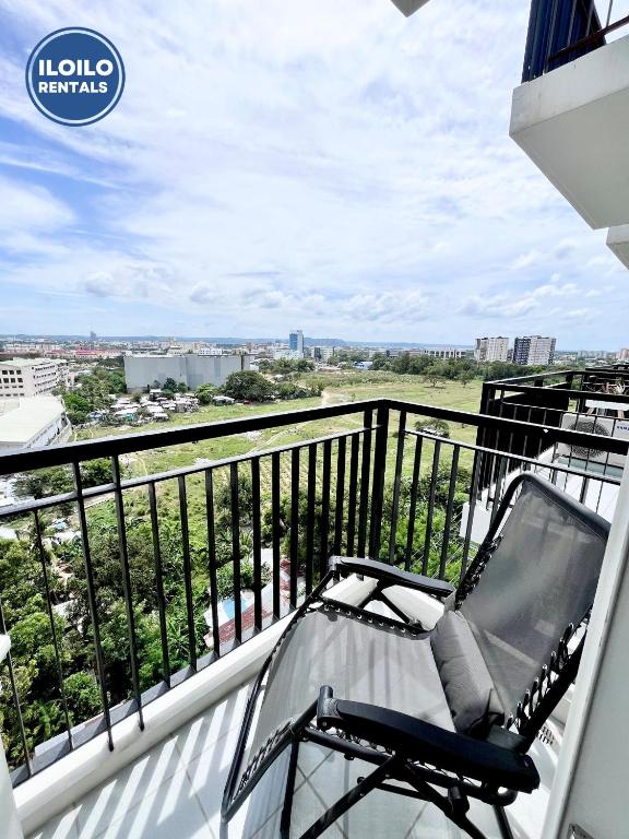 a chair on a balcony with a view of the city at Room in Condo - Cozy, Modern and Homey, The Bliss Studio in Iloilo City