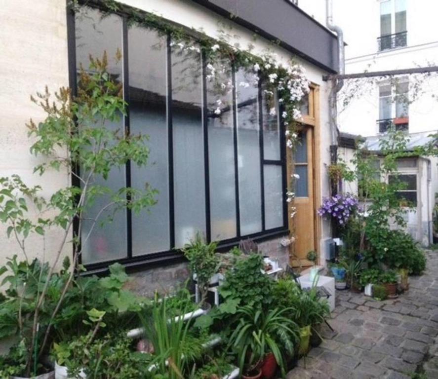 un jardin en face d'une maison ornée de plantes dans l'établissement L'Atelier d'artiste, à Paris