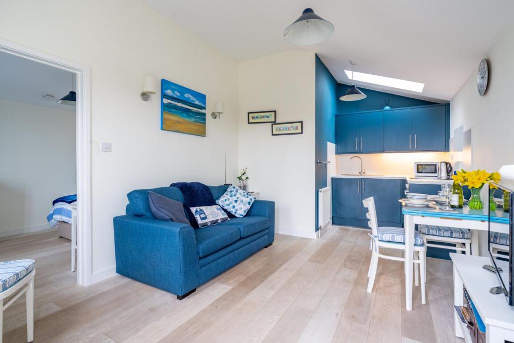 a living room with a blue couch and a kitchen at Little Lammas in Ringstead