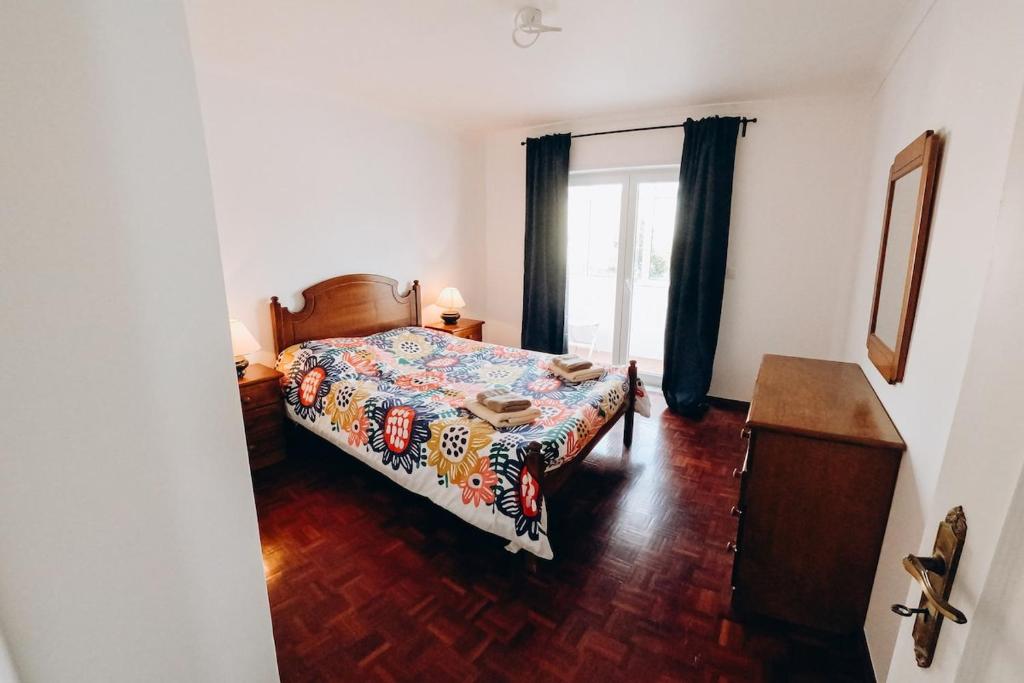 a bedroom with a bed and a window at Um pe na praia in Figueira da Foz
