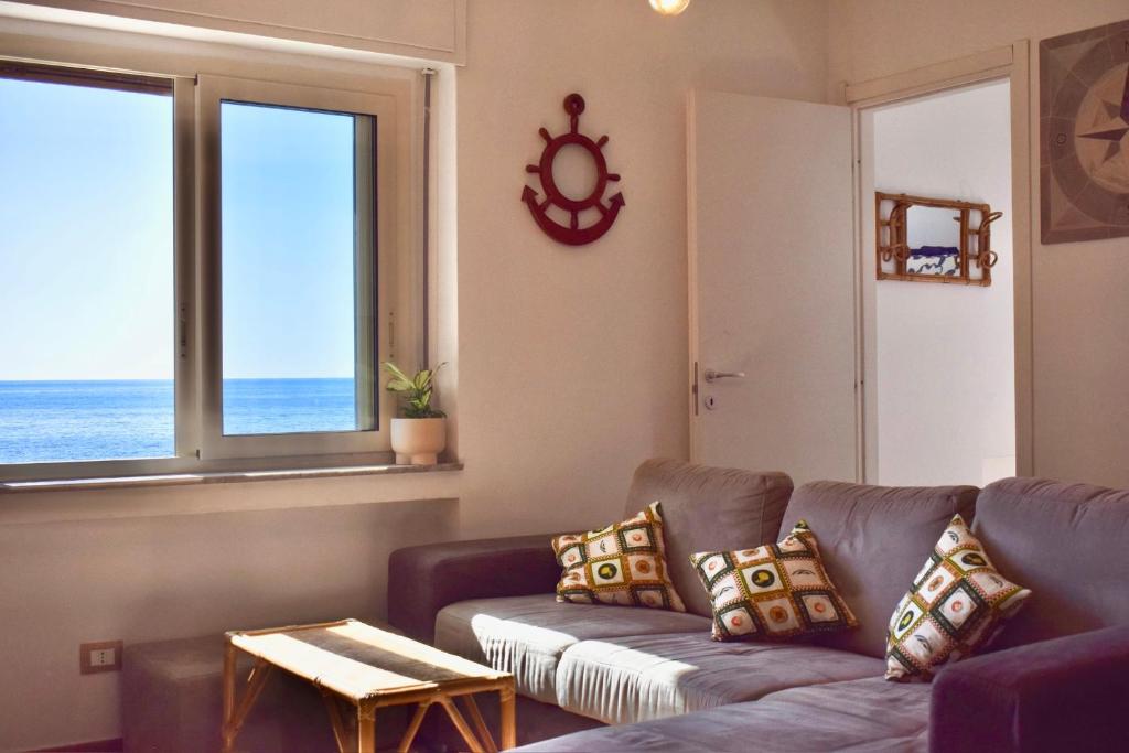 a living room with a couch and a view of the ocean at Wooden Wave Boutique stay in Aci Castello