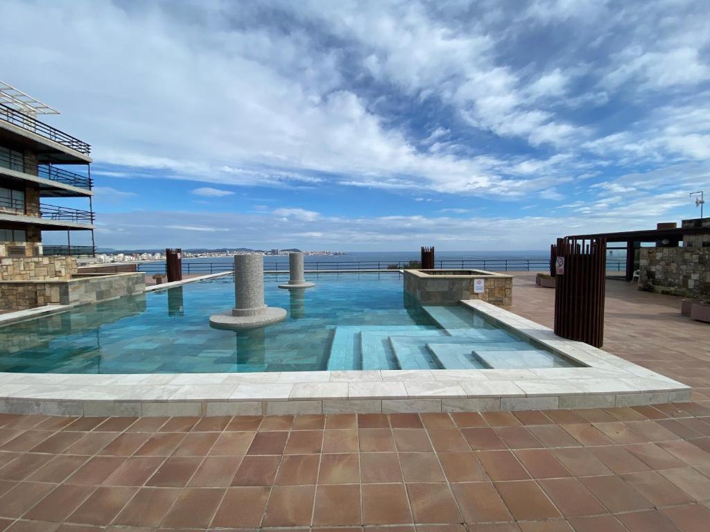 a pool on the roof of a building with the ocean in the background at Eden Mar Sant Antoni de Calonge in Sant Antoni de Calonge