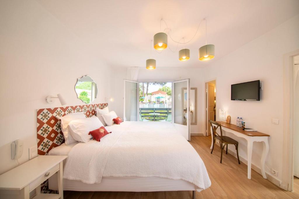 a white bedroom with a large bed and a desk at Les Capucines Saint Tropez in Saint-Tropez