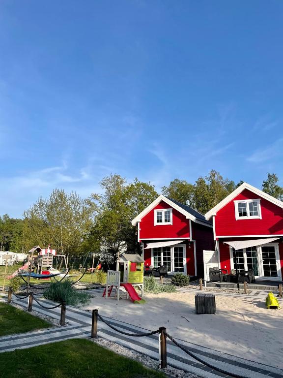two red houses with a playground in front of it at Czerwone Domki in Dębki