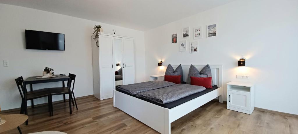 Schlafzimmer mit einem Bett mit roten Kissen und einem Tisch in der Unterkunft Haus Ribeiro in Schluchsee