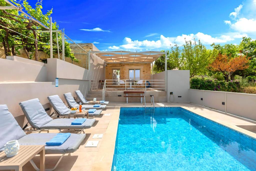 a pool with chaise lounge chairs and a swimming pool at Cretan Breeze Villa Beheizter Privater Swimmingpool in Dhrámia