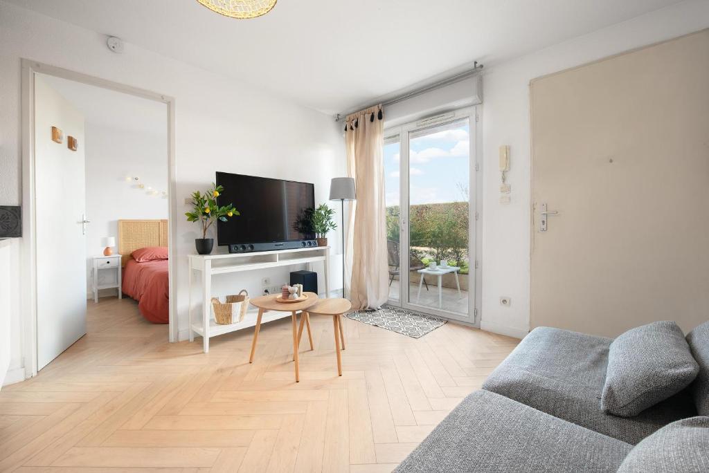 a white living room with a couch and a table at Joli T2 avec terrasse et Parking in Toulouse