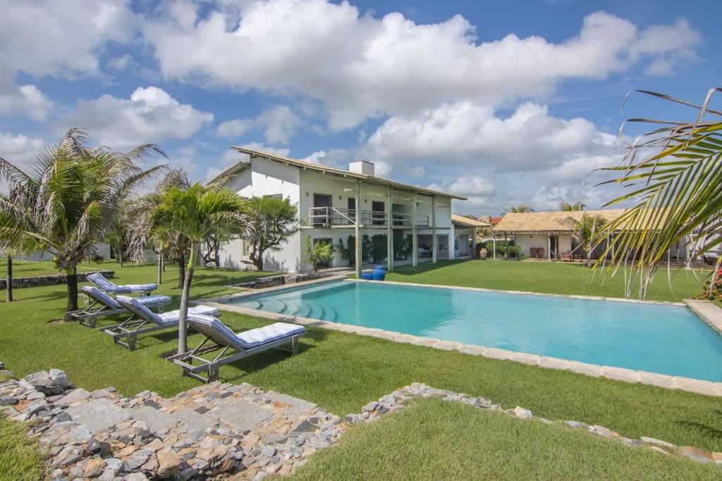 ein Swimmingpool vor einem Haus mit Palmen in der Unterkunft Tudo Bom Kitesurf Dream Villa in Taíba