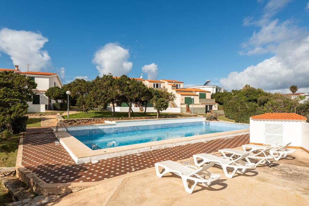 a swimming pool with lounge chairs next to a house at Menorca Apartamento ALOHA by Mauter Villas in Cala en Blanes