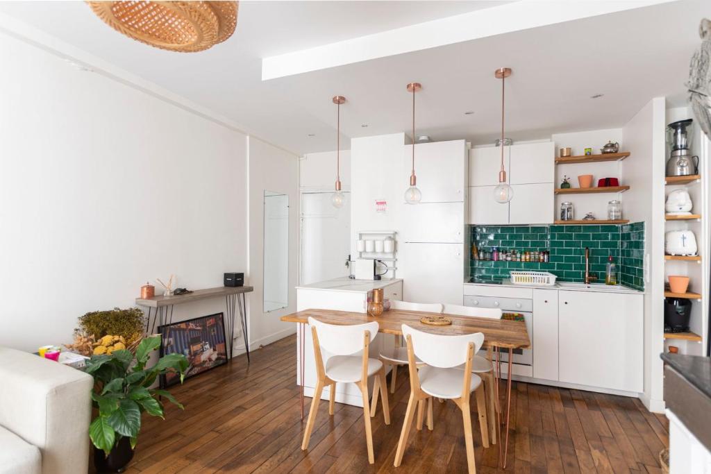 une cuisine avec des armoires blanches et une table et des chaises en bois dans l'établissement GuestReady - Charming Central Apt near Les Halles, à Paris
