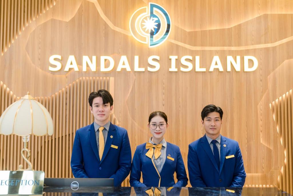 a group of three men in suits standing in front of a sign at SANDALS ISLAND HOTEL in Nha Trang