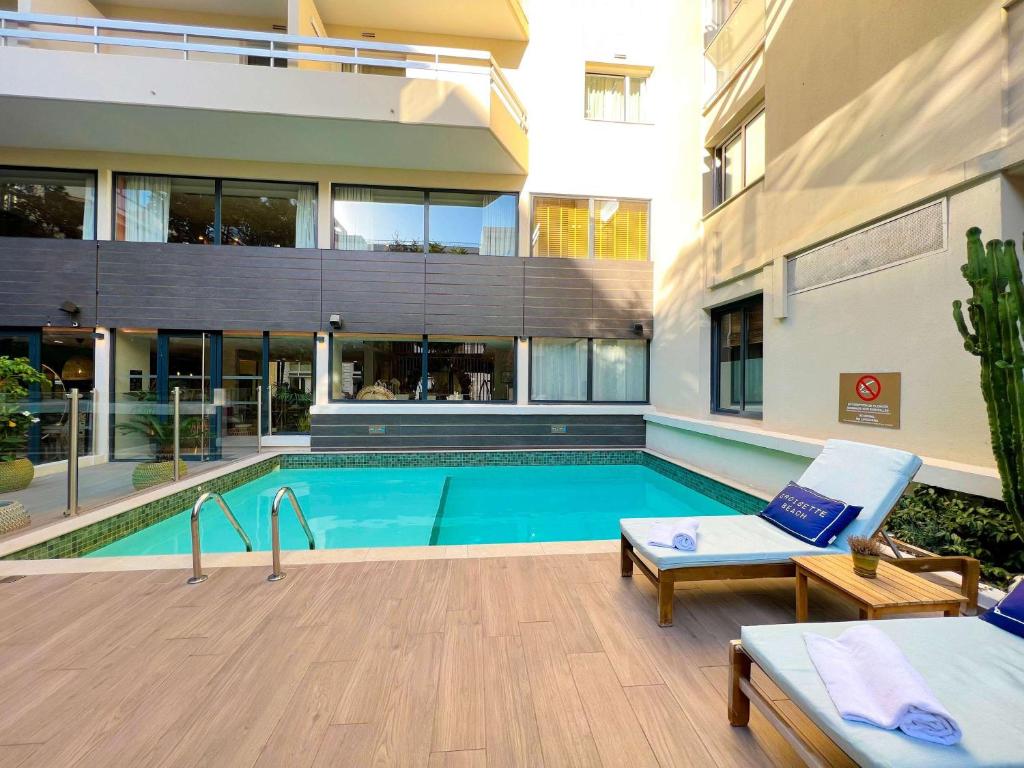 a swimming pool in front of a building at Croisette Beach Hotel Cannes - MGallery Collection in Cannes