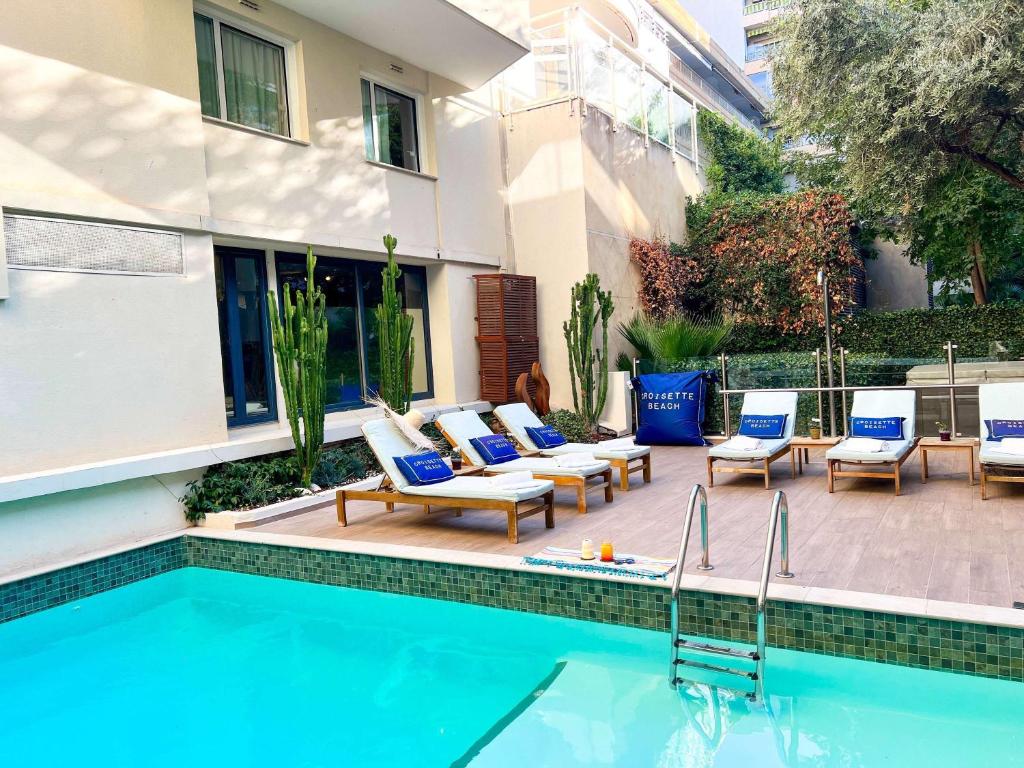 a patio with chairs and a swimming pool at Croisette Beach Hotel Cannes - MGallery Collection in Cannes
