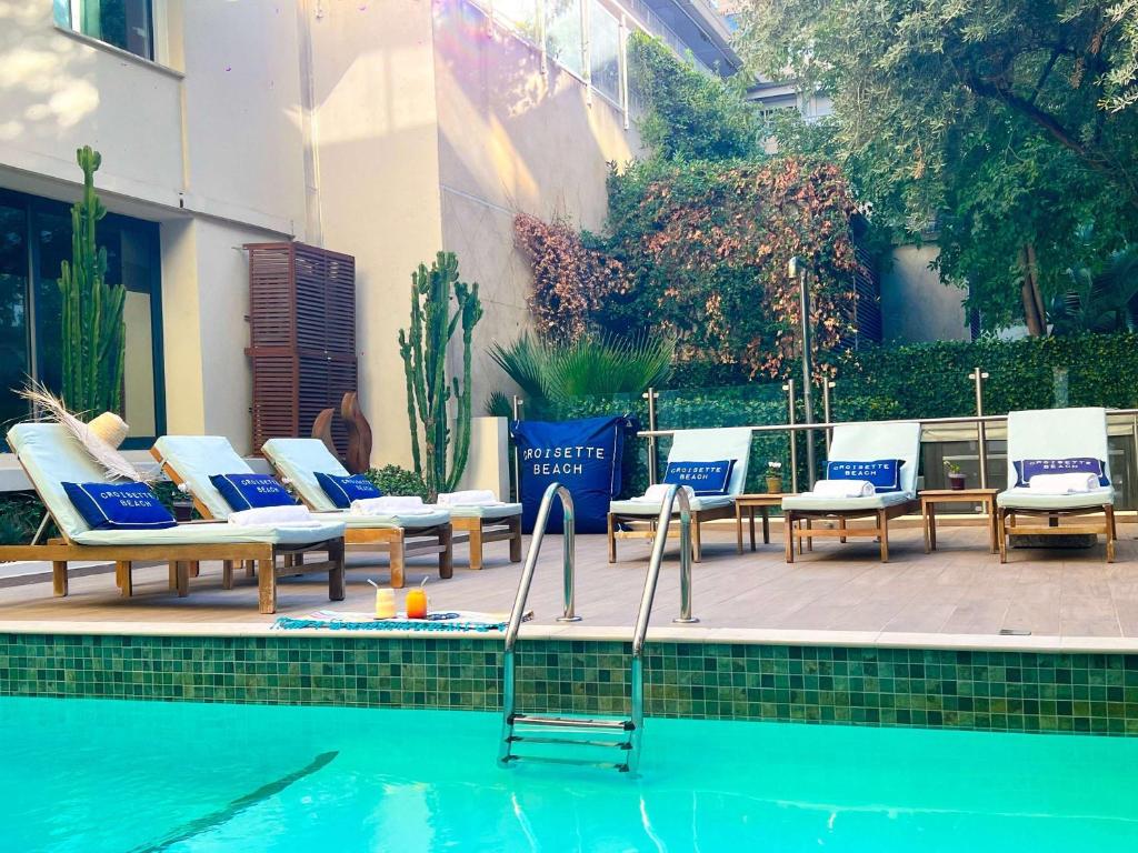 a group of lounge chairs and a swimming pool at Croisette Beach Hotel Cannes - MGallery Collection in Cannes