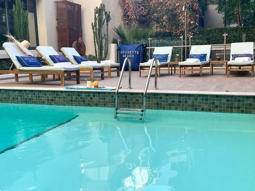 a swimming pool with chaise lounges and chairs next to a swimming pool at Croisette Beach Hotel Cannes - MGallery Collection in Cannes