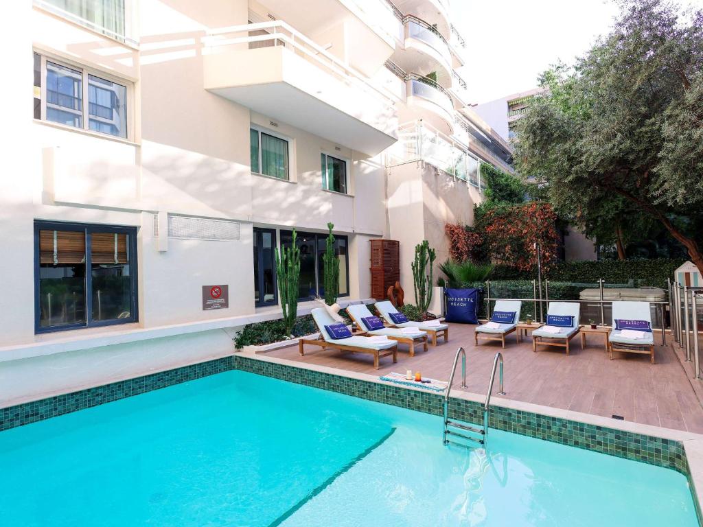 a swimming pool in front of a building at Croisette Beach Hotel Cannes - MGallery Collection in Cannes