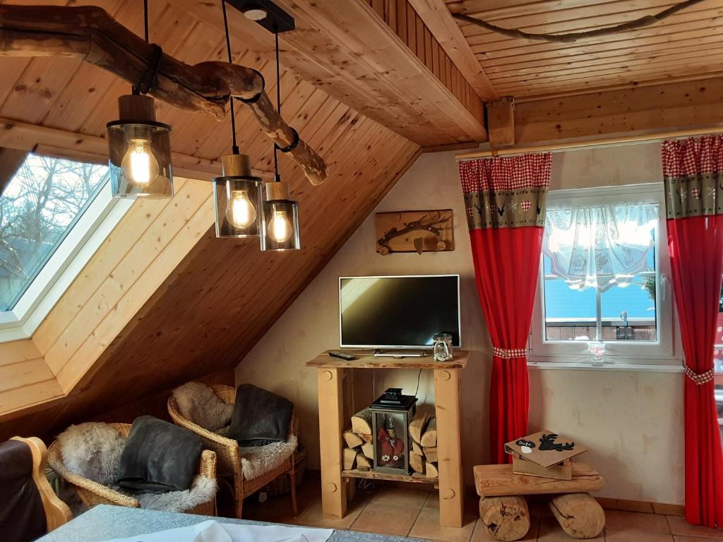 sala de estar con TV y 2 ventanas en Fewo Holzwurm, en Braunlage