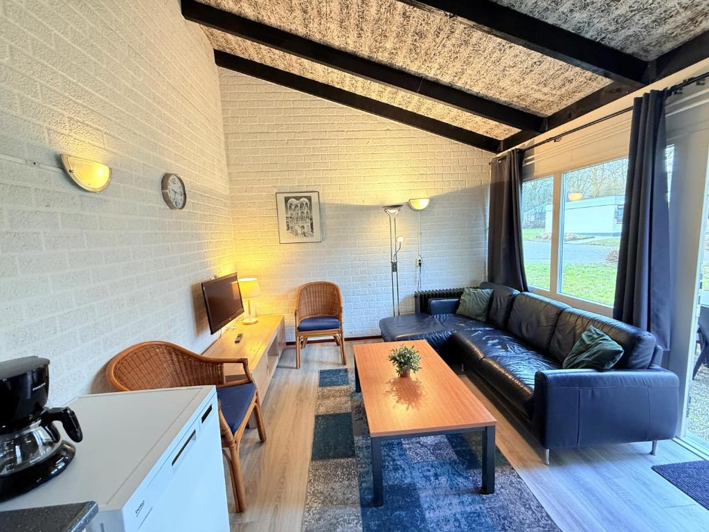 a living room with a couch and a table at Bungalowpark Simpelveld - Schakel 15 in Simpelveld