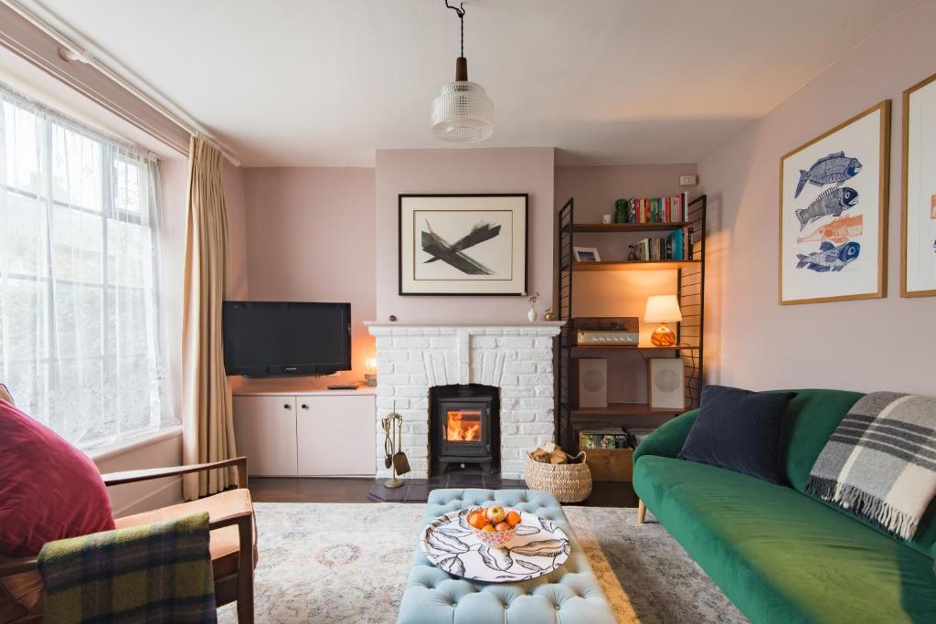 a living room with a green couch and a fireplace at Seafarer by Keepers Cottages in Kingsdown