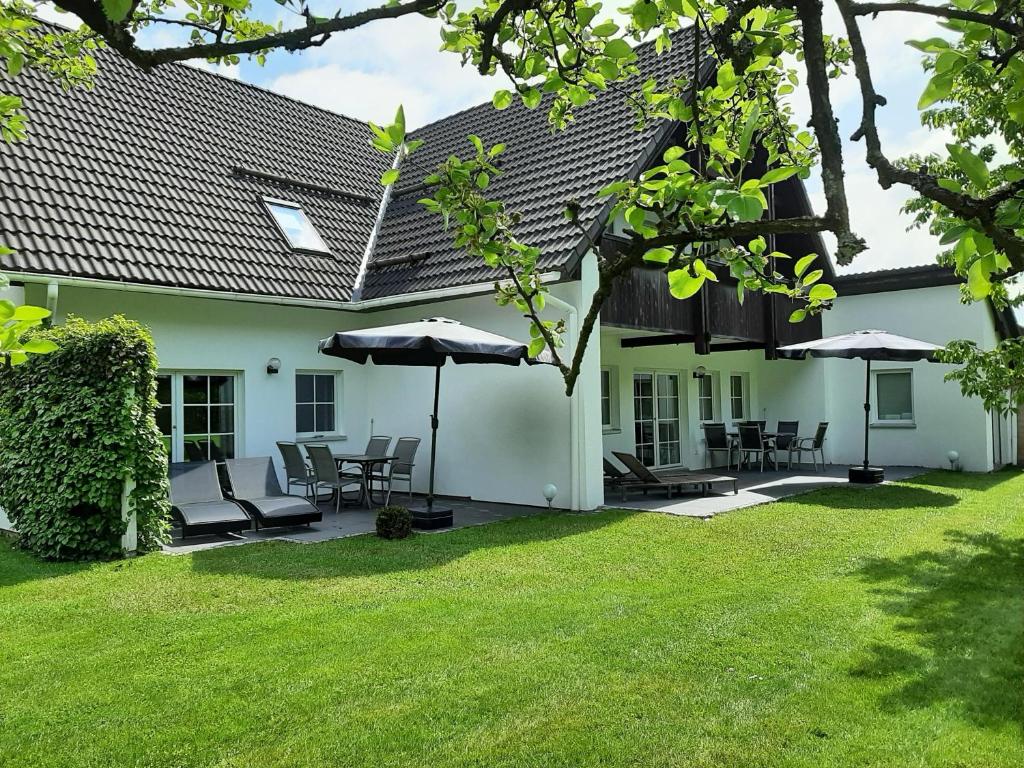 a white house with chairs and tables and umbrellas at Fewo Stricker 31 in Walkenried