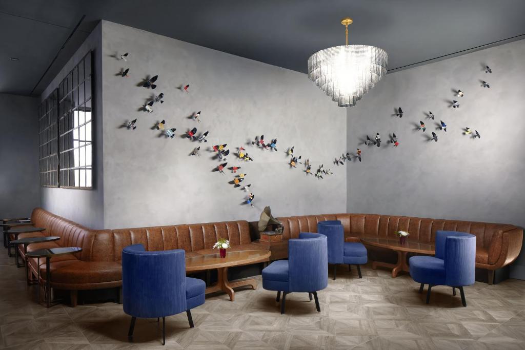 a restaurant with tables and blue chairs and birds on the wall at Hotel Van Zandt in Austin